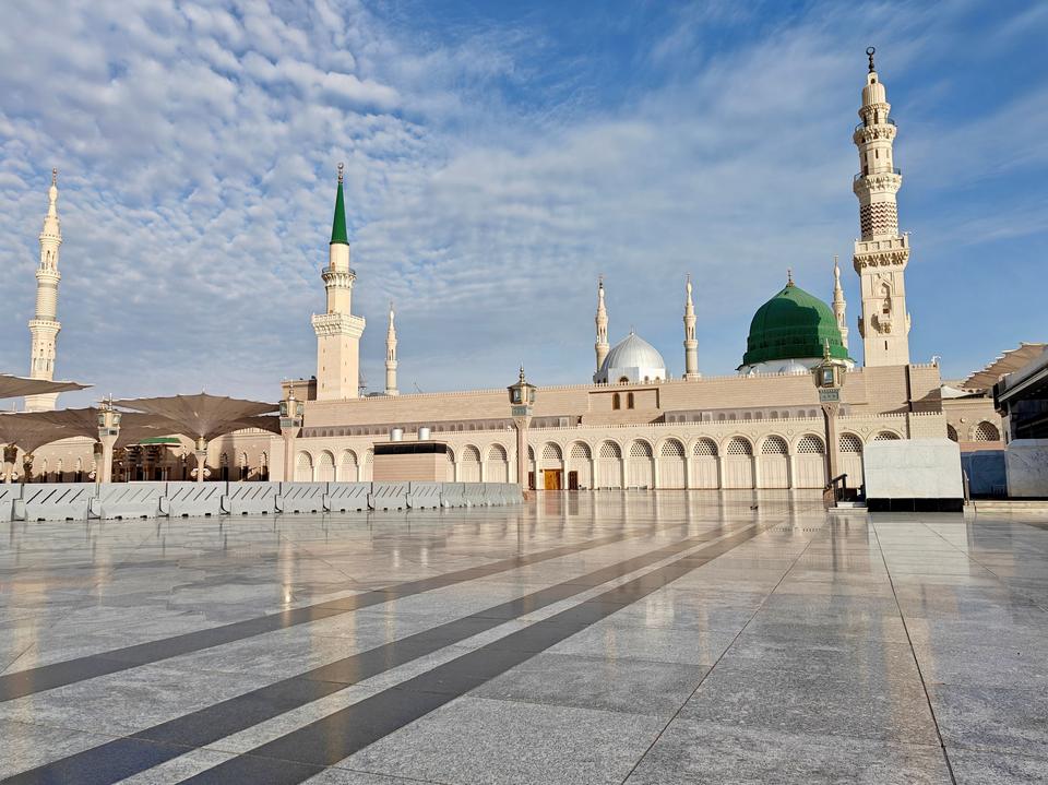 Al-Masjid an-Nabawi in Madinah on a clear morning: white minarets, the green dome and the marble courtyard.